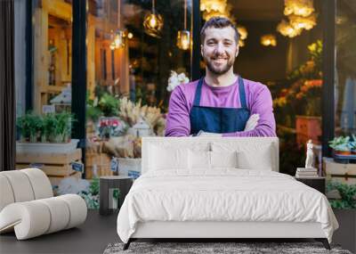 Flower shop owner in an apron has his arms crossed in front of his flower store. Wall mural