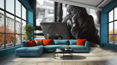 A woman is sitting at a table with a laptop and a cup of coffee Wall mural