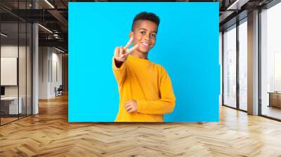 African American boy over isolated blue background smiling and showing victory sign Wall mural