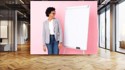 African american business woman giving a presentation on white board over isolated pink background looking side Wall mural