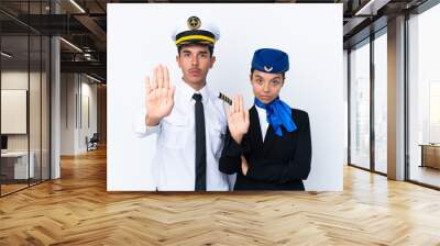 Airplane pilot and mixed race air hostess isolated on white background making stop gesture denying a situation that thinks wrong Wall mural