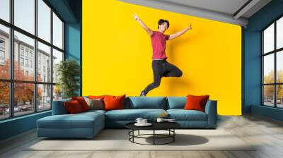 Asian man jumping over isolated yellow wall Wall mural