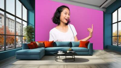 Asian young girl listening music with a mobile and dancing over isolated purple wall Wall mural