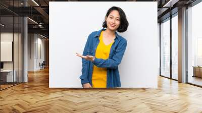 Asian young woman over isolated white background presenting an idea while looking smiling towards Wall mural