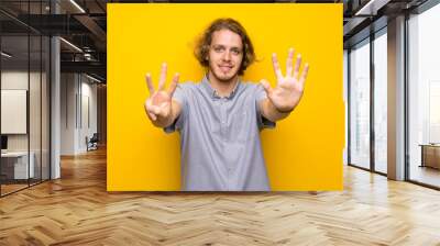 Blonde man over isolated yellow background counting eight with fingers Wall mural