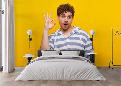 Blonde man over yellow wall surprised and showing ok sign Wall mural