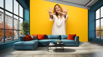 Blonde woman over yellow wall counting ten with fingers Wall mural