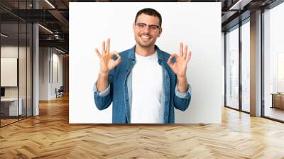 Brazilian man over isolated white background showing ok sign with two hands Wall mural