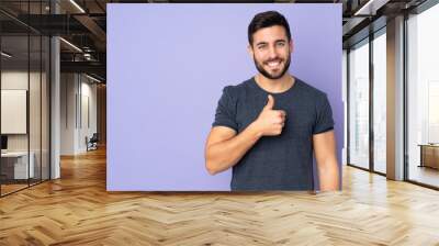 Caucasian handsome man giving a thumbs up gesture over isolated purple background Wall mural