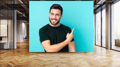 Caucasian handsome man isolated on blue background pointing to the side to present a product Wall mural