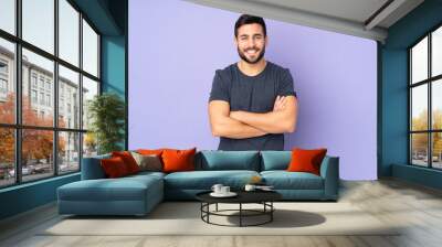 Caucasian handsome man keeping the arms crossed in frontal position over isolated purple background Wall mural