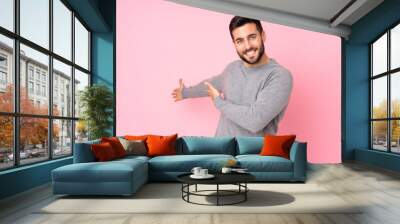 Caucasian handsome man over isolated background extending hands to the side for inviting to come Wall mural