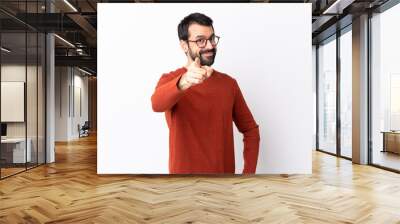 Caucasian handsome man with beard over isolated white background points finger at you with a confident expression Wall mural