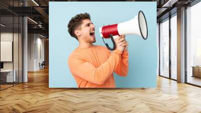 Caucasian man isolated on blue background shouting through a megaphone Wall mural