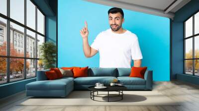 Caucasian man over isolated blue background showing and lifting a finger in sign of the best Wall mural