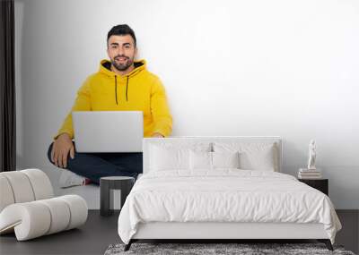 Caucasian man sitting on the floor with his laptop laughing Wall mural