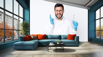 Dentist man holding tools isolated on white background laughing Wall mural