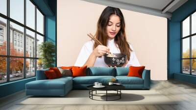 Girl holding a bowl full of noodles over isolated background Wall mural