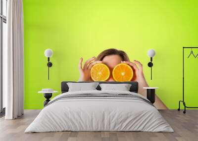 girl with oranges in her eyes over green background Wall mural