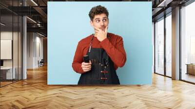 Hairdresser caucasian man isolated on blue background thinking an idea Wall mural