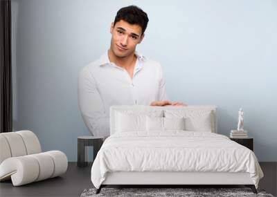 Handsome man over blue wall presenting an idea while looking smiling towards Wall mural