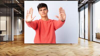 Handsome man over isolated blue background making stop gesture and disappointed Wall mural