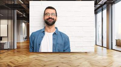 Handsome man with beard over white brick wall laughing Wall mural