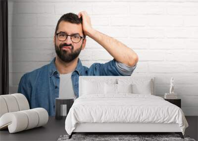 Handsome man with beard over white brick wall with an expression of frustration and not understanding Wall mural