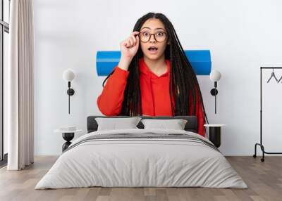 Hiker teenager girl with braids over isolated white background with glasses and surprised Wall mural