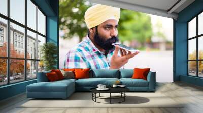 Indian with turban using mobile phone in outdoors Wall mural