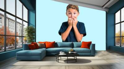 Little boy is a little bit nervous and scared on blue background Wall mural