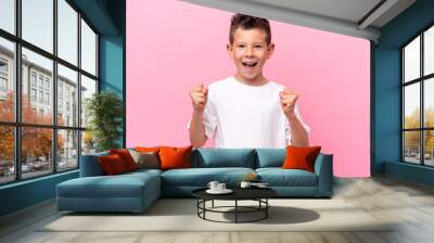 Little caucasian boy isolated on pink background celebrating a victory in winner position Wall mural