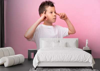 Little caucasian boy isolated on pink background having doubts and thinking Wall mural