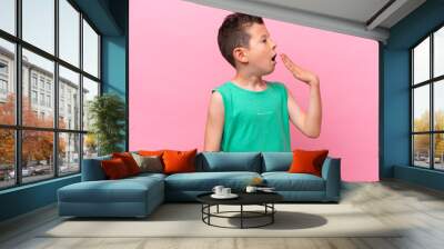 Little caucasian boy isolated on pink background yawning and covering wide open mouth with hand Wall mural