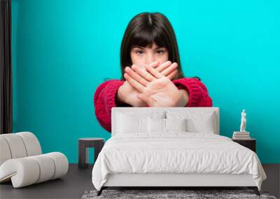 Little caucasian girl isolated on blue background making stop gesture with her hand to stop an act Wall mural