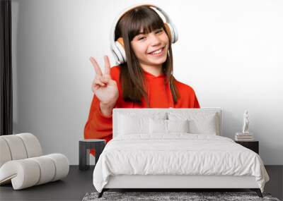 Little caucasian girl playing with a video game controller over isolated background smiling and showing victory sign Wall mural