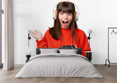 Little caucasian girl playing with a video game controller over isolated background with shocked facial expression Wall mural