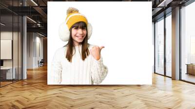 Little caucasian girl wearing winter muffs over isolated background pointing to the side to present a product Wall mural