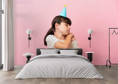 Little caucasian kid with birthday hat isolated on pink background suffering from pain in shoulder for having made an effort Wall mural