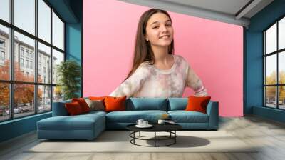 Little girl over isolated pink background posing with arms at hip and smiling Wall mural