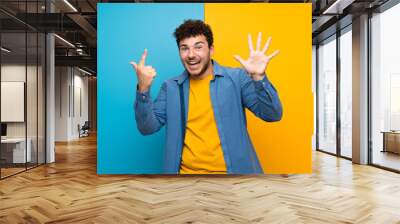 Man with curly hair over colorful wall counting seven with fingers Wall mural