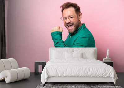 Middle age caucasian man isolated on pink background celebrating a victory Wall mural