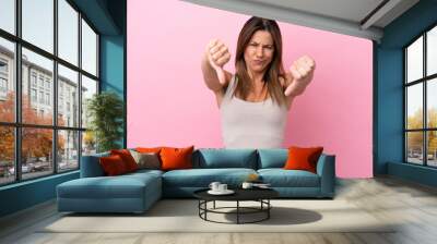 Middle age caucasian woman isolated on pink background showing thumb down with two hands Wall mural