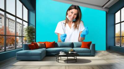 Middle age doctor woman isolated on blue background making money gesture Wall mural