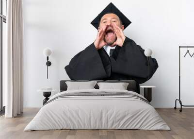 Middle age university graduate man isolated on white background shouting and announcing something Wall mural