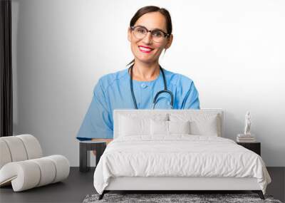 Middle-aged nurse woman over isolated background keeping the arms crossed in frontal position Wall mural