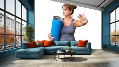 Middle-aged sport woman going to yoga classes while holding a mat over isolated background making stop gesture and disappointed Wall mural