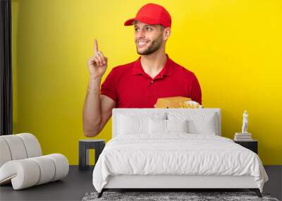 pizza delivery man picking up pizza boxes and burgers over isolated background pointing up a great idea Wall mural