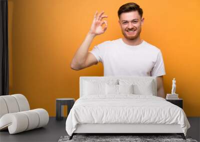 Redhead man over brown wall showing ok sign with fingers Wall mural