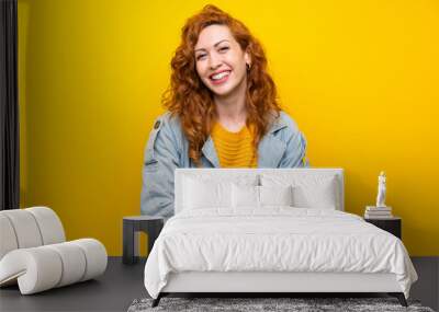 Redhead woman over isolated yellow background laughing Wall mural